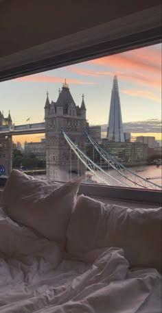 a bed sitting in front of a window with a view of the bridge and buildings