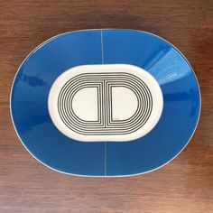 a blue and white plate with the letter d on it sitting on a wooden surface