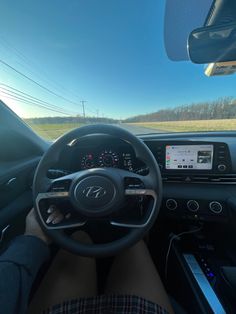 a person is sitting in the driver's seat of a car with their feet on the steering wheel