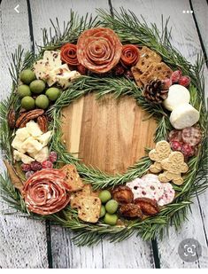 a wreath made out of different types of food on a wooden table with pine cones