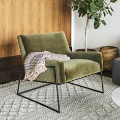 a green chair sitting on top of a rug next to a potted plant