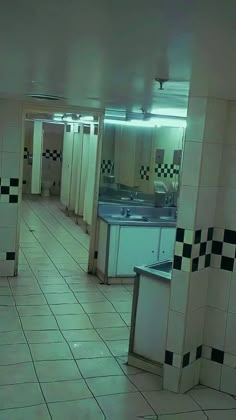 an empty public restroom with black and white tiles on the floor, sinks and stalls