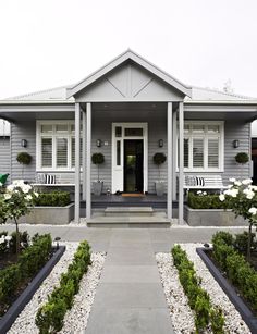 an image of a house with flowers in the front yard and on the side door