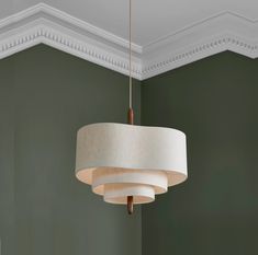 a chandelier hanging from the ceiling in a room with green walls and white trim