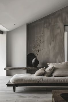 a black and white photo of a bed in a room with wooden floors, vases on the wall