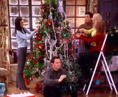 friends decorating a christmas tree on the set of friends and family tv show in their living room