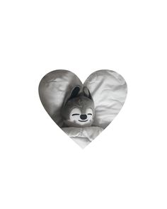 a stuffed animal in the shape of a heart on top of a sheeted pillow