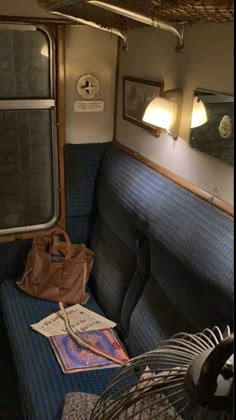 the inside of a train car with blue seats and luggage on it's side