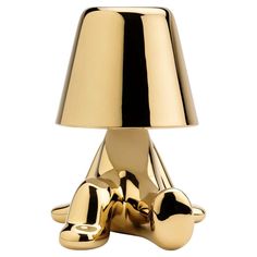 a gold table lamp sitting on top of a white floor next to a light bulb