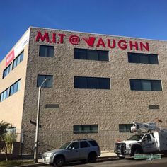 two trucks parked in front of a building with a large sign on it's side