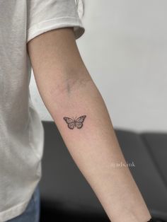 a woman's arm with a small butterfly tattoo on the left side of her arm