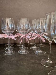 six wine glasses with pink bows are lined up in a row on a counter top