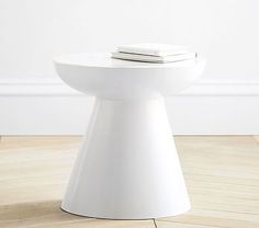 a white toilet sitting on top of a hard wood floor next to a book shelf