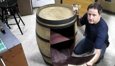 a man kneeling down next to a wooden barrel