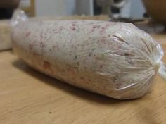 a piece of food wrapped in plastic sitting on top of a wooden table