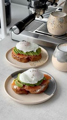 two plates with sandwiches on them next to an espresso machine