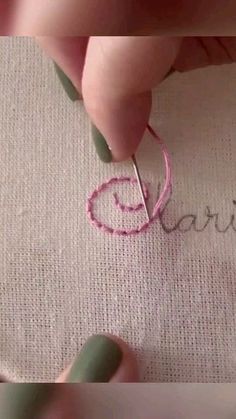 someone is doing something with some thread on the fabric and using scissors to make it