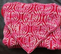 a pink and white crocheted blanket on a black leather surface