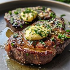 two steaks on a plate topped with sauce and green garnish, ready to be eaten