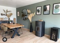 a dining room table with chairs and pictures on the wall above it, next to a wood burning stove