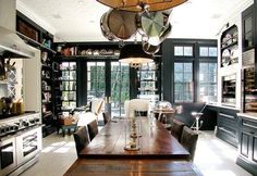 a large wooden table sitting in the middle of a kitchen next to an oven and stove