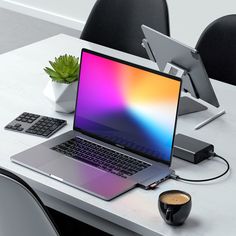 an open laptop computer sitting on top of a white table next to a cup of coffee