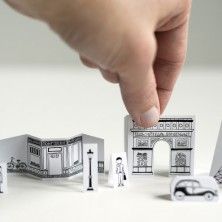 a hand is pointing at some miniature buildings