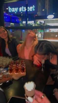 three women sitting at a table with food and drinks