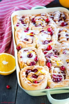 cranberry orange rolls in a baking dish with icing