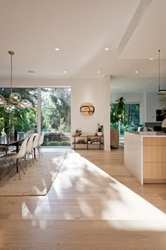 a dining room table and chairs in front of an open kitchen with sliding glass doors