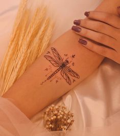 a woman's arm with a dragonfly tattoo on the left side of her right arm