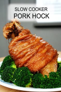 a piece of pork with broccoli on a white plate that says slow cooker pork hock