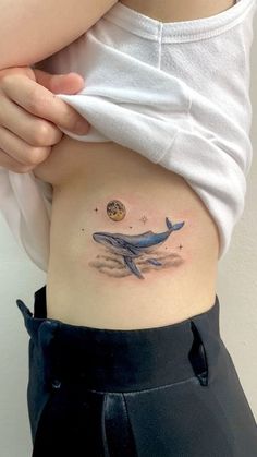 a woman's stomach with a whale tattoo on her belly and the moon above it