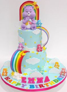 a birthday cake with a teddy bear on top and rainbow decorations around the edges,