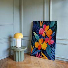 a painting sitting on top of a wooden floor next to a lamp