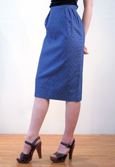 "This is a classic vintage 1960s blue paisley print pencil skirt. It features vertical pleats below the waistband, a center walking vent in the back, and a hem that ends just below the knee. It has a stylized, subtle floral paisley pattern, in turquoise green and navy blue on a deep blue background. The fabric is a sturdy cotton with a satin lining inside at the waist. The skirt closes with a button at the left hip and a 6 inch metal side zipper that is expertly placed, so that it is completely Retro Fitted Knee-length Skirt, Spring Retro Fitted Pencil Skirt, Retro Fitted Pencil Skirt For Spring, Retro Blue Lined Skirt Bottoms, Vintage Fitted Knee-length Pencil Skirt, Retro Fitted Knee-length Pencil Skirt, Retro Fitted Lined Pencil Skirt, Vintage Knee-length Pencil Skirt For Spring, Vintage Blue Skirt For Work