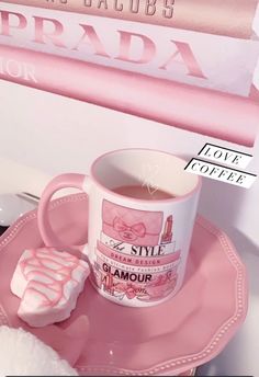 a cup of coffee and some marshmallows on a pink plate with a sign in the background