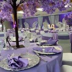 the tables are set with purple napkins and place settings