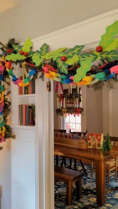 a table and chairs in a room decorated with paper garlands on the ceiling, along with christmas decorations