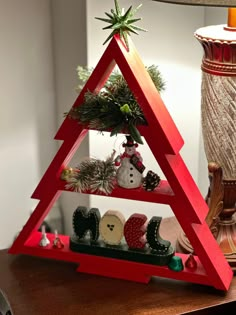 a christmas tree made out of red wooden triangles on a table next to a lamp