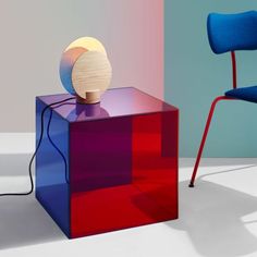 a colorful table with a lamp on it next to a blue chair in the background