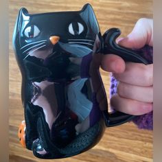 a person holding a black cat mug in their hand