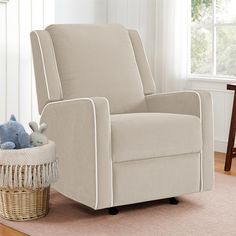 a chair with a teddy bear in it next to a basket on the floor near a window