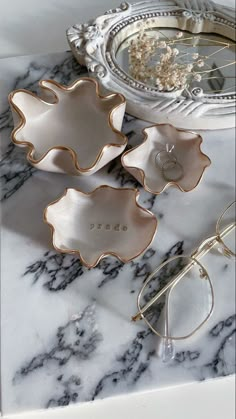 three decorative dishes sitting on top of a marble counter next to a pair of glasses