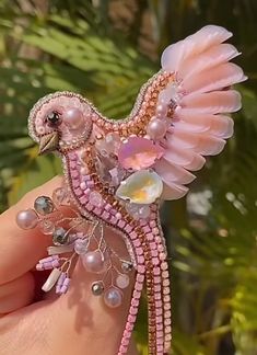 a pink bird brooch sitting on top of someone's hand