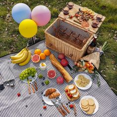 a picnic table with food and balloons on it, including fruit, crackers, bread, cheeses, and wine