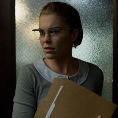 a woman in glasses holding a brown box