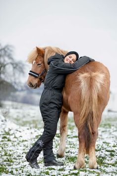 a person hugging a horse in the snow