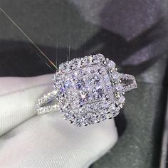 a close up of a person's hand holding a diamond ring