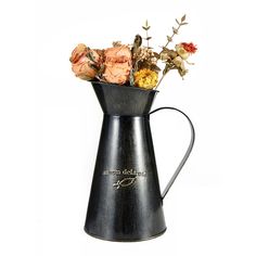 a metal pitcher with flowers in it